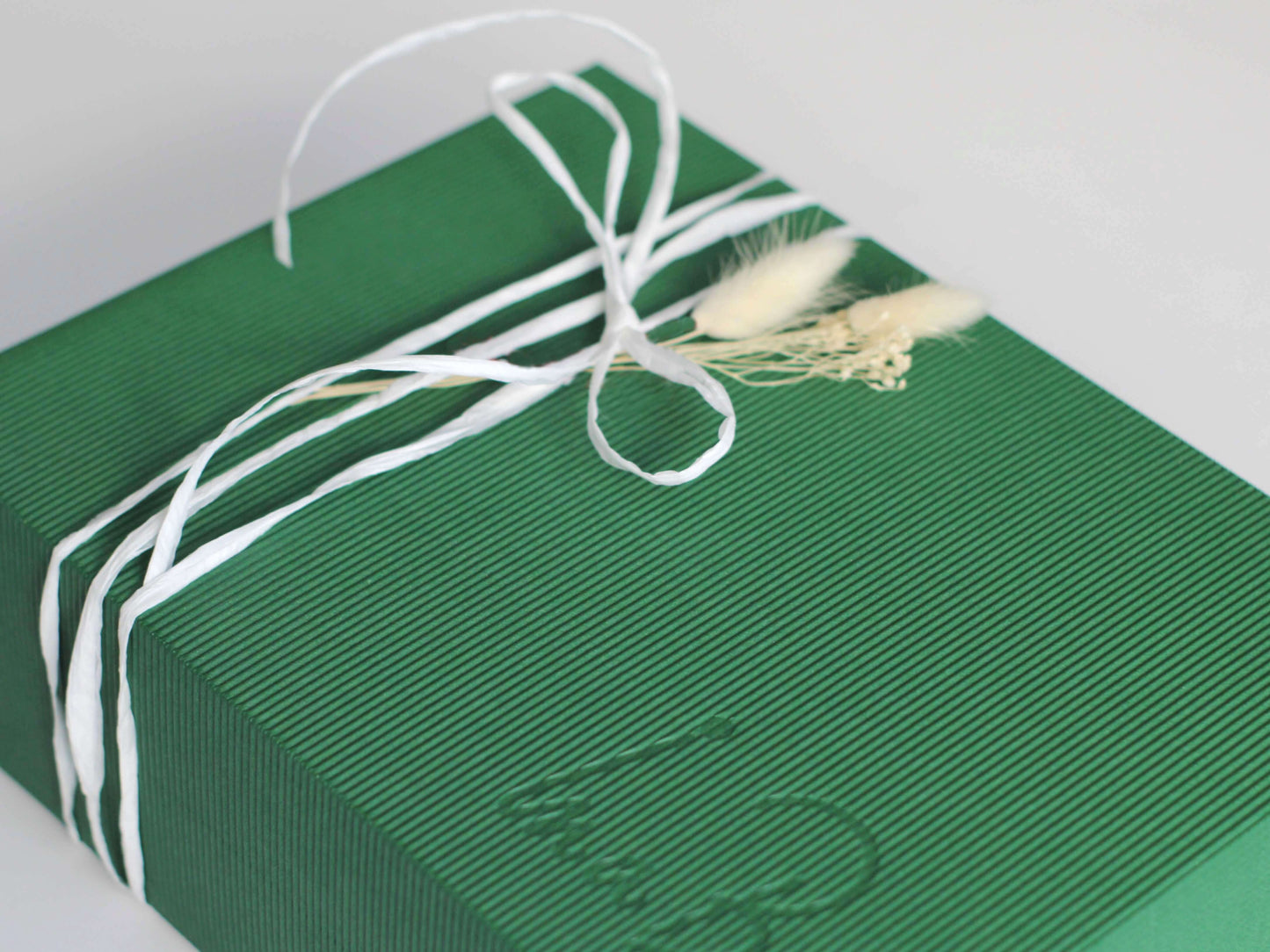 cadou romanesc gata de daruit, legat cu panglica din hartie alba si decorat cu buchetel natural